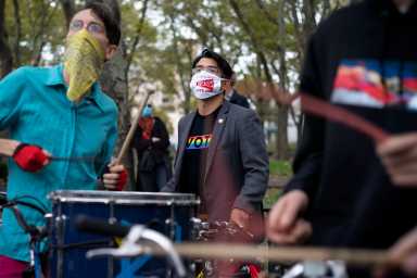 Councilman Carlos Menchaca, wearing "Ruckus Vote 2020" mask, behind a group of drummers performing. (Photo credit: Tsubsa Berg)
