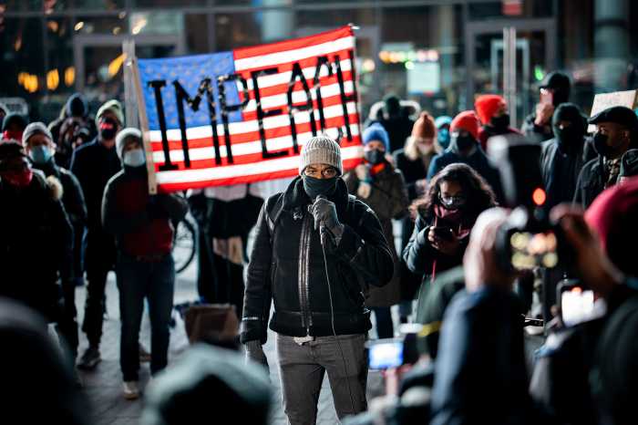 Public Advocate Jumaane Williams surrounded by the protesters speaking to a microphone.