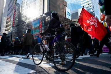 Protesters marching in Times Square. One of the protester carrying DSA flag on his shoulder.