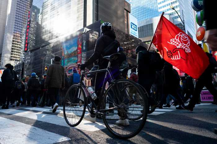 Protesters marching in Times Square. One of the protester carrying DSA flag on his shoulder.