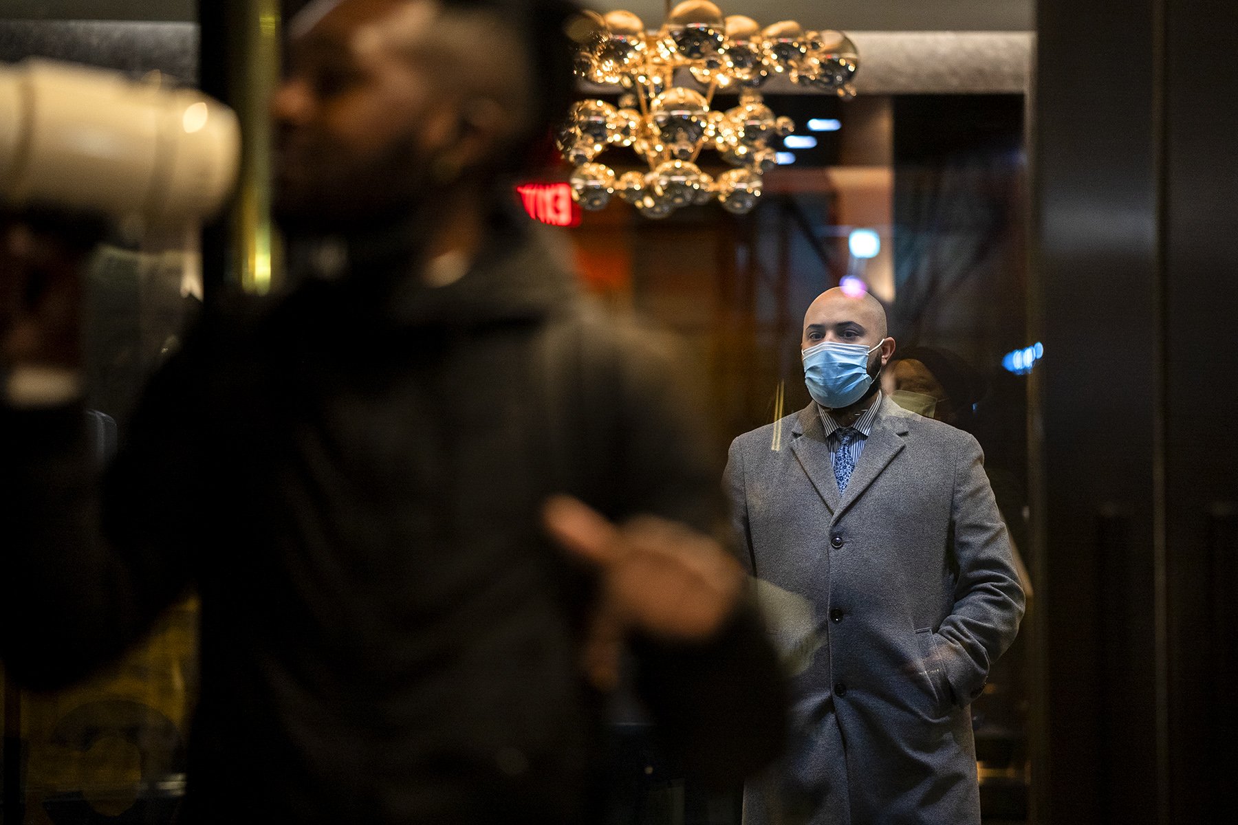 A man in winter overcoat looking out at the rally taking place outside (Photo credit: Tsubasa Berg)