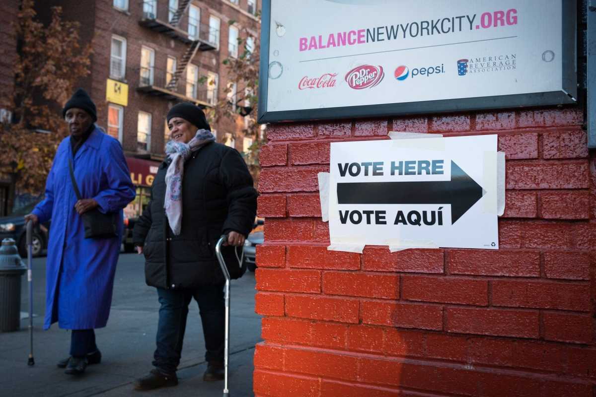Two ladies walking with canes to voting lcation. "Vote Here/Vote Aqui" sign directing voters to the voting location.