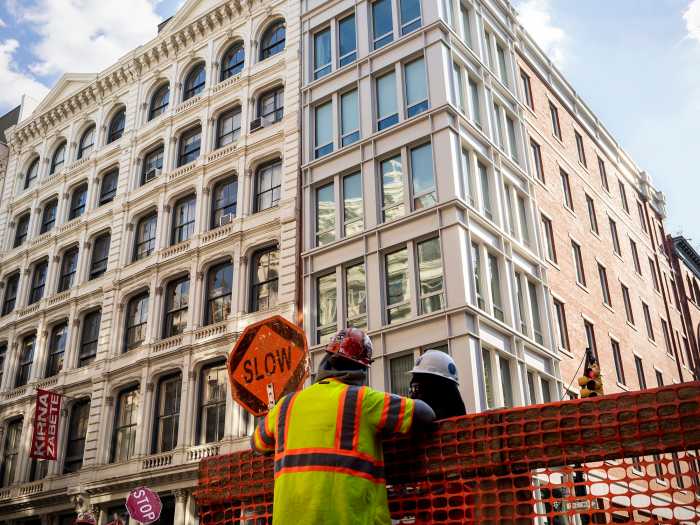 Construction workers holding up "Slow" sign at a construction site in SOHO