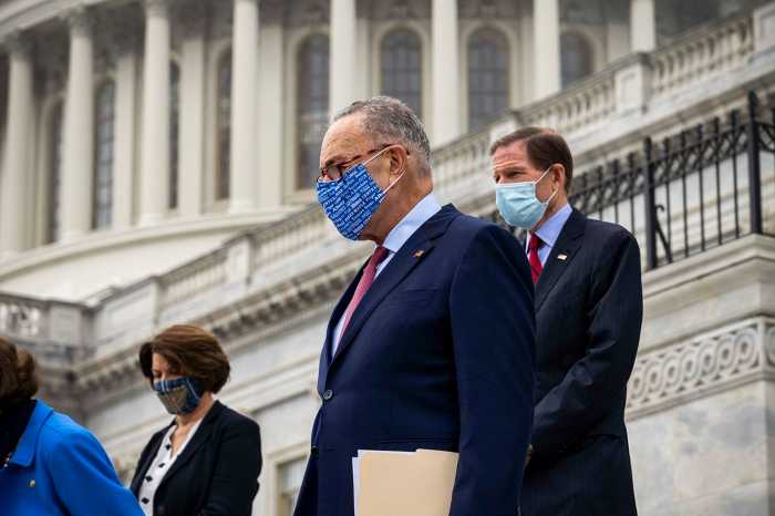 Senator Chuck schumer wearing blue mask, ascending stairs U.S. Capital building in D.C.