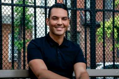 Phelan Dante Fitzpatrick sitting at a park, smiling to the camera