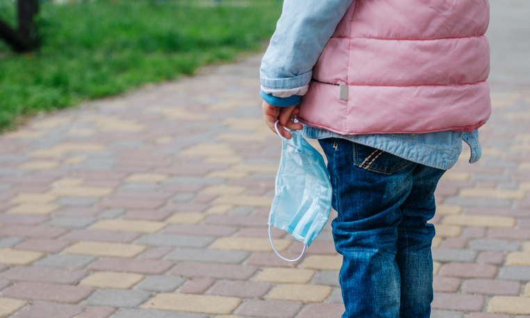 Close up of little girl holding protective face mask outside